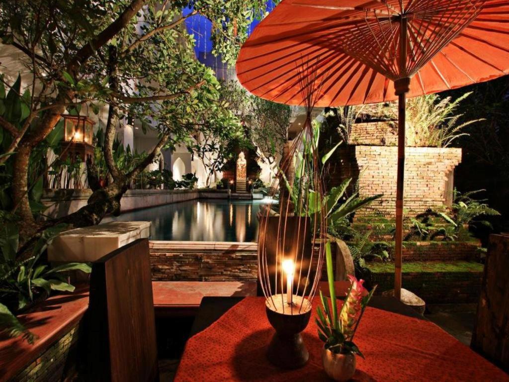 a table with an umbrella and a candle on it at Gudi Boutique Resort in Mae Rim