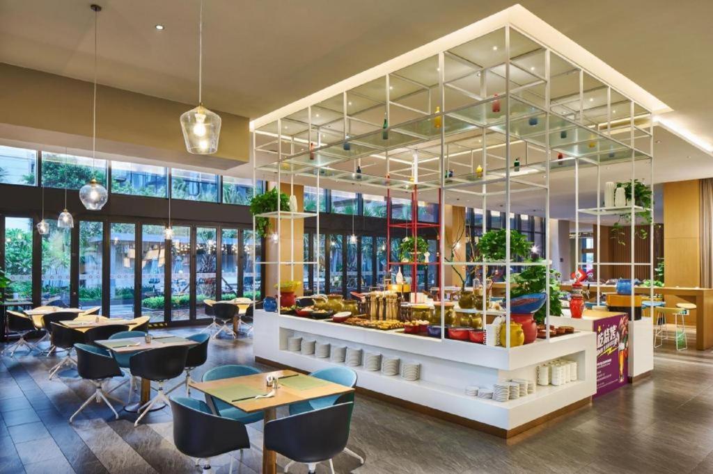 a restaurant with tables and chairs and windows at Four Points by Sheraton Haikou International Airport in Haikou