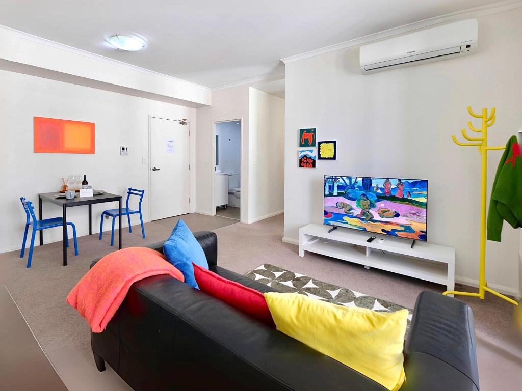 Una sala de estar con un sofá negro y una mesa. en Super Convenient 1BR Apt Free Parking & study, en Sídney
