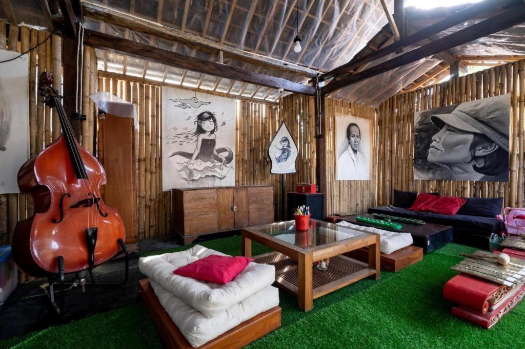 a living room with a large guitar and a couch at Hotel O Putroyono Homestay in Mendut
