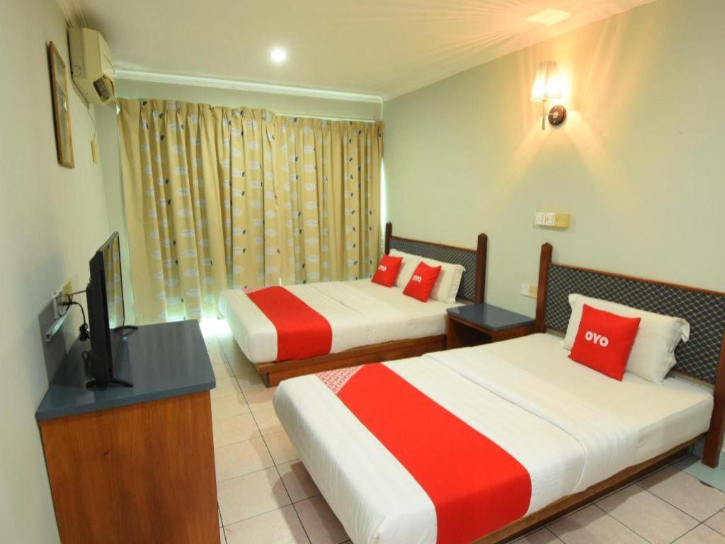 a hotel room with two beds and a flat screen tv at OYO 89642 Highway Inn in Mukah