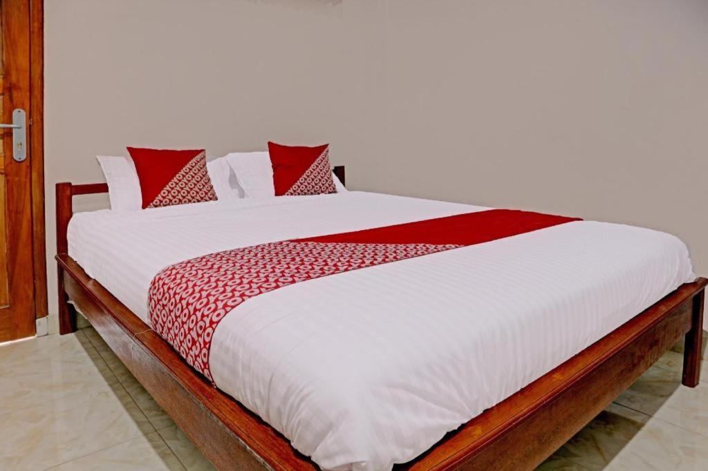 a large bed with red and white sheets and pillows at Hotel O Mulia Bangka in Pangkalan Baru