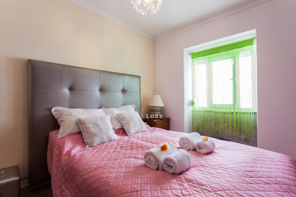 una camera da letto con un letto rosa e asciugamani di Apartamento Cardoso ad Albufeira