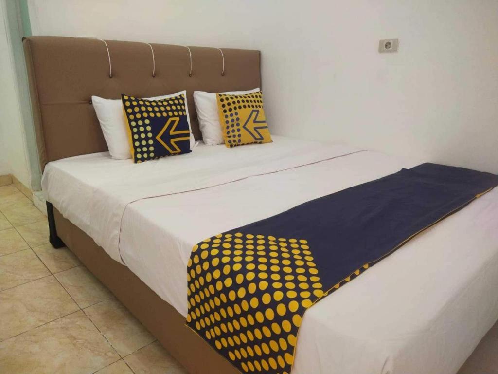 a bed with yellow and blue pillows on it at SPOT ON 93478 Amanda Residence Syariah in Palembang