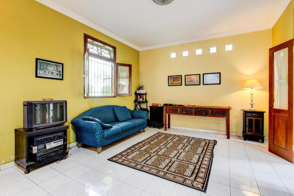 ein Wohnzimmer mit einem blauen Sofa und einem Fernseher in der Unterkunft Capital O 93938 Wisma Pamungkas Syariah in Ngemplak