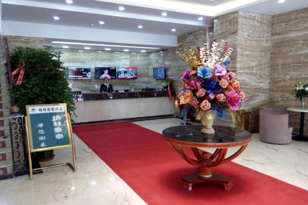 a lobby with a vase of flowers on a red rug at GreenTree Inn Geermu Walking Street Business Hotel in Golmud