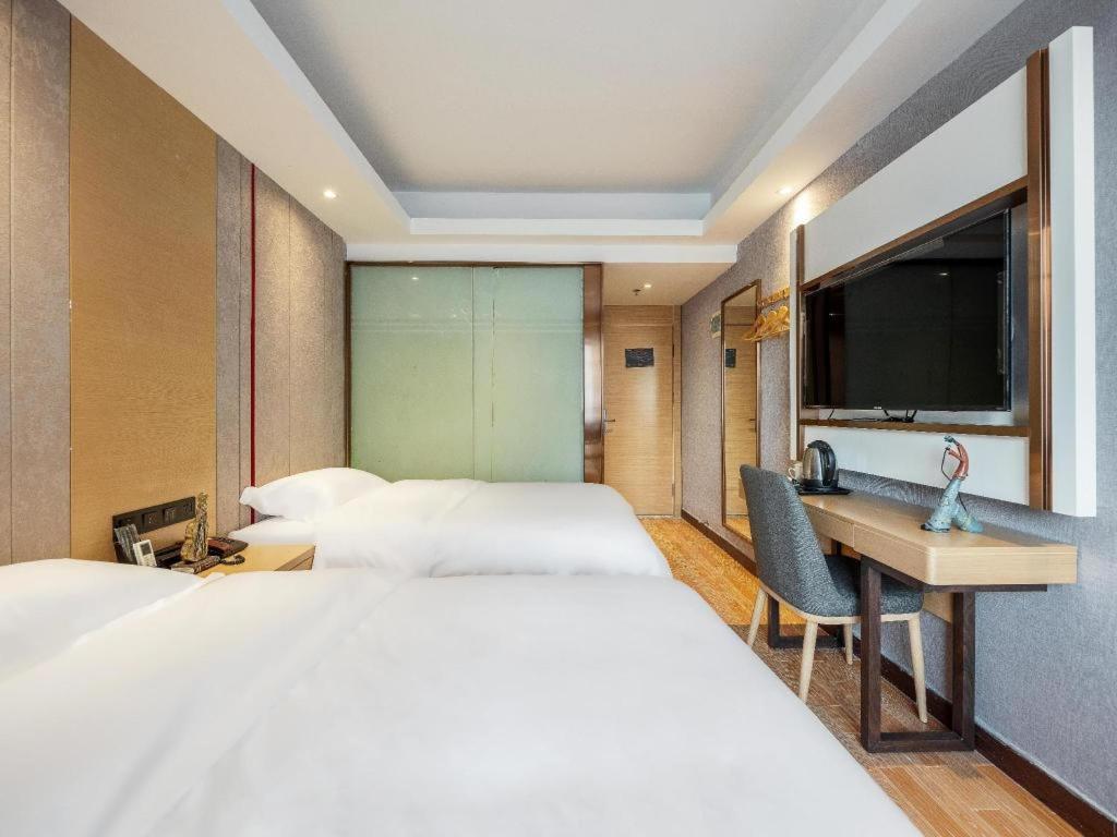 a hotel room with two beds and a desk and a television at Yimi Hotel Guangzhou Yuexiu Park North Branch in Guangzhou