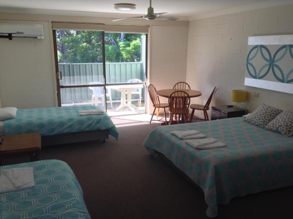 Habitación de hotel con 2 camas, mesa y sillas en Settlers Inn en Port Macquarie