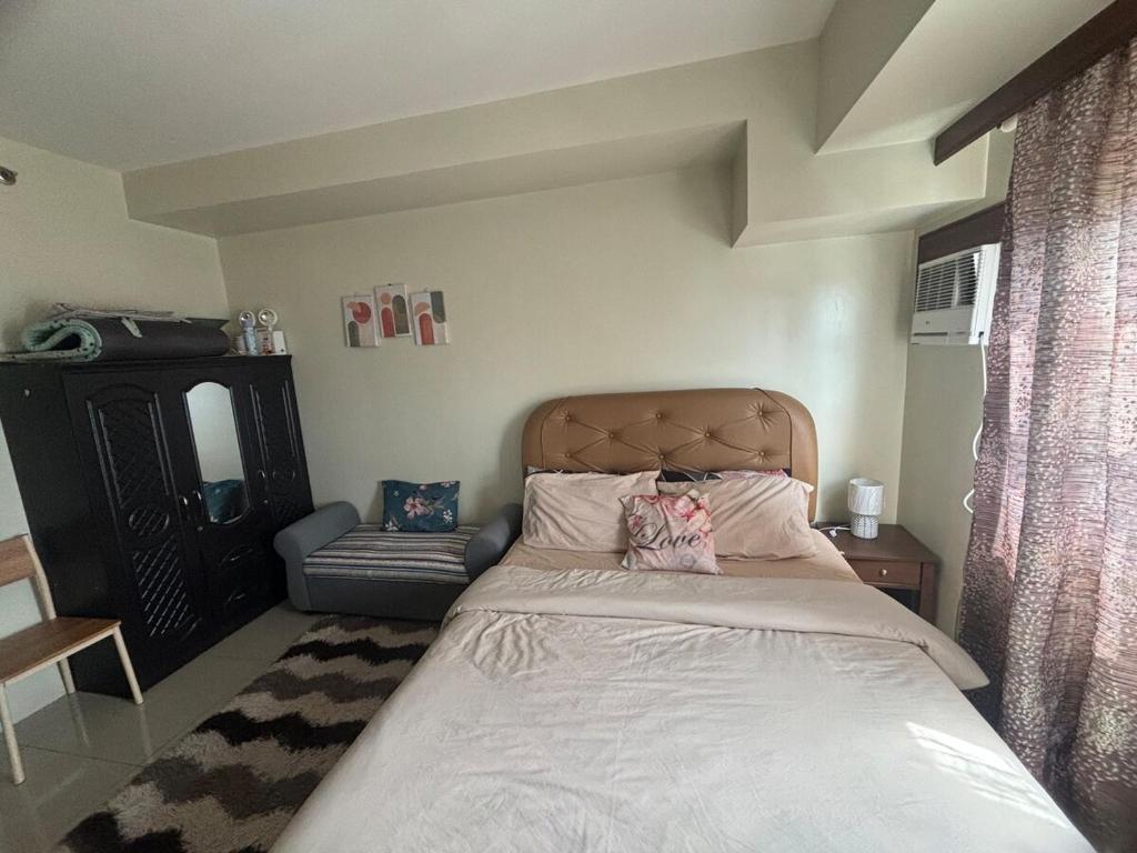 een slaapkamer met een bed en een stoel bij Cozy and Affordable Studio Unit in Cebu City
