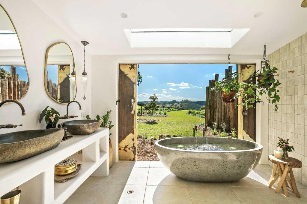La salle de bains est pourvue de 2 lavabos et d'une grande baignoire. dans l'établissement Meadows Cottage, à Bangalow
