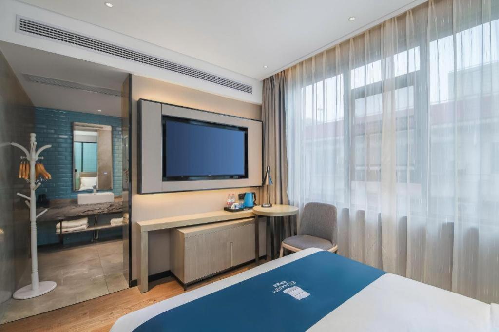 Echarm Hotel Changsha Wuyi Square Xiangya Affiliated 1st Provincial Maternity and Child في تشانغشا: غرفة فندقية مع سرير وتلفزيون بشاشة مسطحة