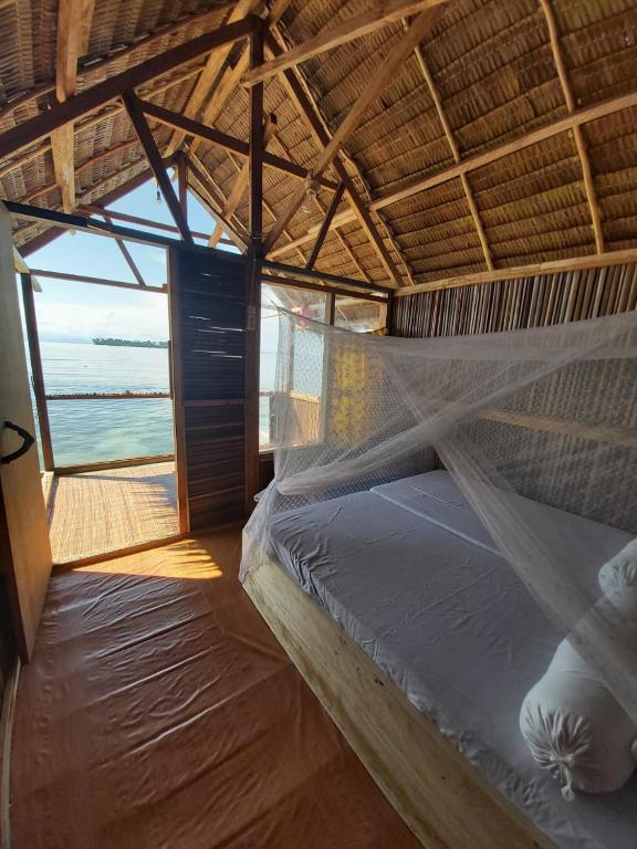 a bed in a room with a view of the ocean at Kasumasa Homestay in Fambemuk
