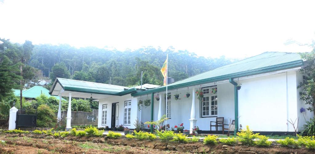 a white building with a flag on top of it at Silver Meir Bungalow in Nuwara Eliya