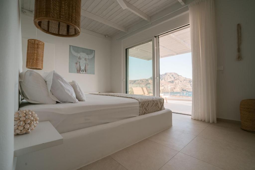 a white bedroom with a large bed and a large window at Villa Sávra in Plakias