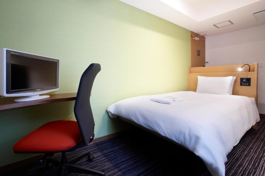 a hotel room with a bed and a red chair at the b ikebukuro in Tokyo