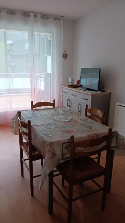 a dining room with a table and chairs and a television at 31 avenue GEORGES CLEMENCEAU in Le Mont-Dore