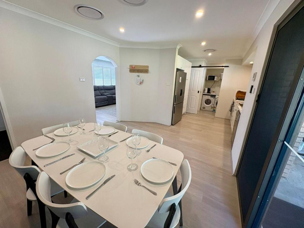 una mesa de comedor blanca con sillas blancas en una habitación en Broadwater Beach Cottage, en Broadwater