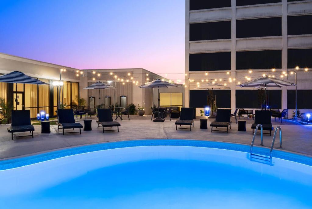 a pool in front of a building with chairs and umbrellas at Wyndham Indianapolis Airport in Indianapolis