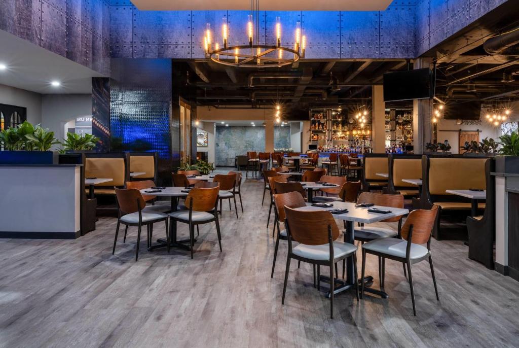 a restaurant with tables and chairs and a bar at Wyndham Indianapolis Airport in Indianapolis