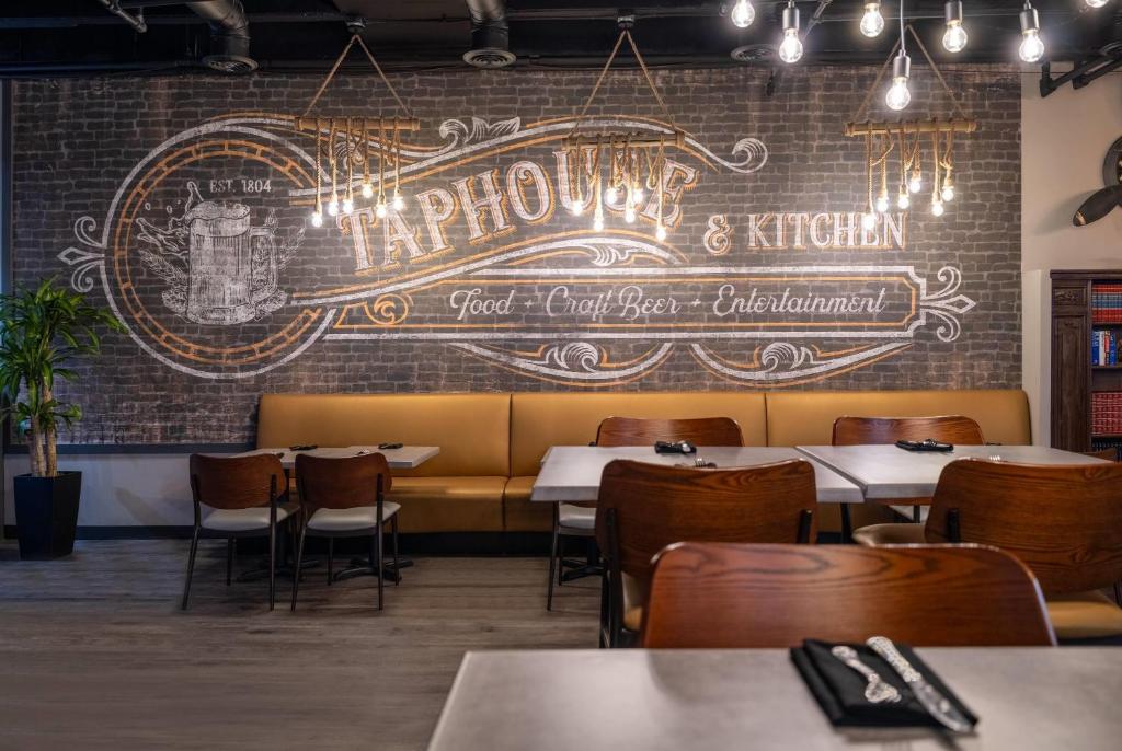 a restaurant with tables and chairs and a brick wall at Wyndham Indianapolis Airport in Indianapolis