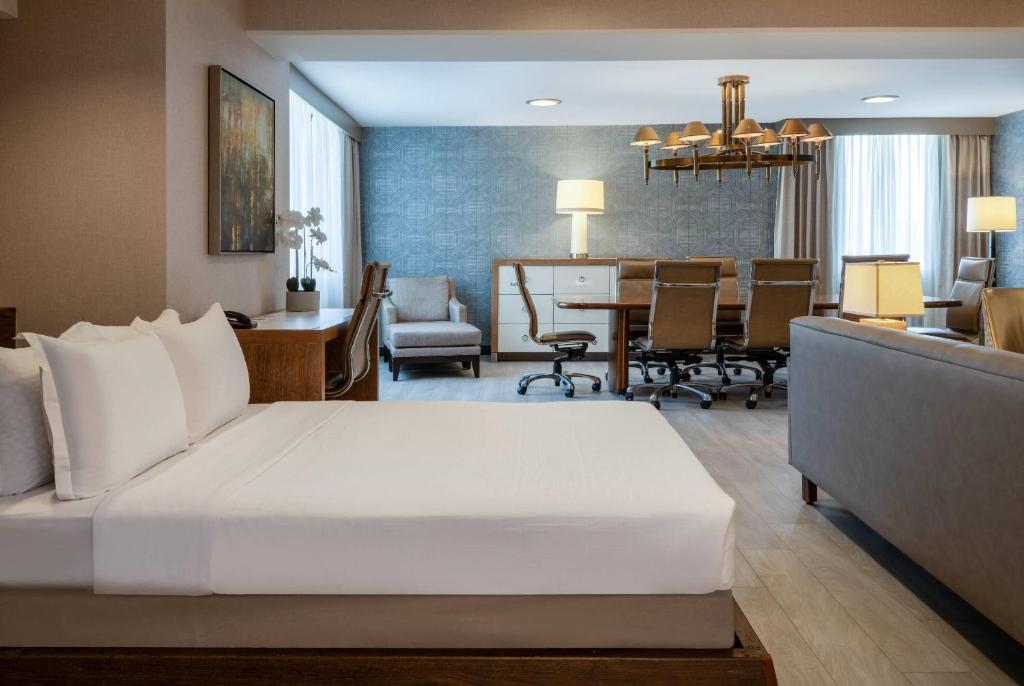 a bedroom with a large bed and a dining room at Wyndham Indianapolis Airport in Indianapolis