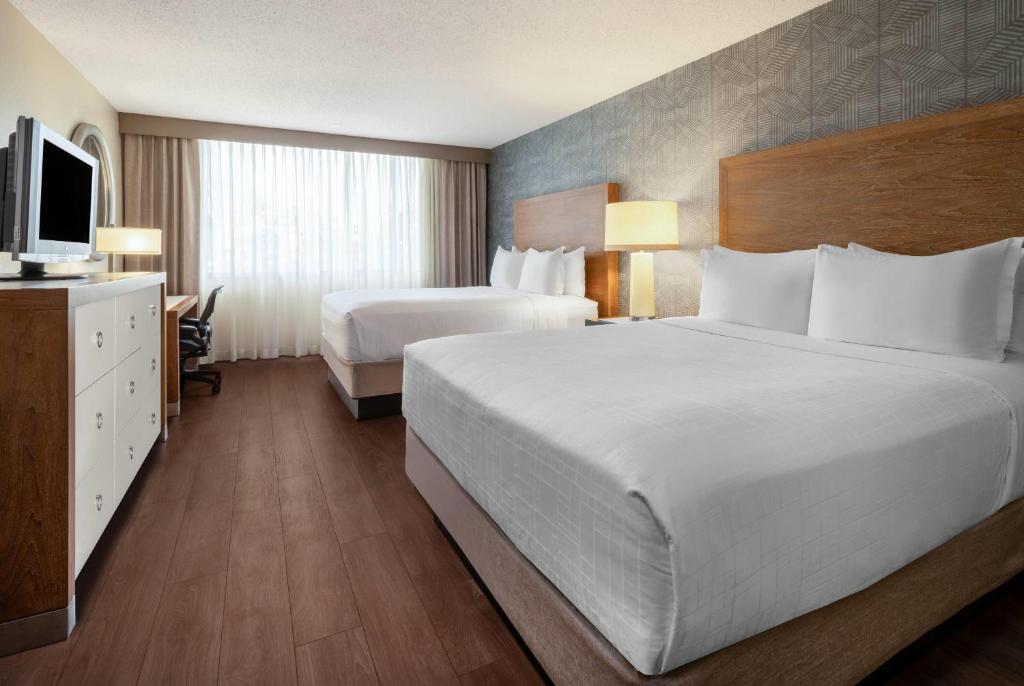 a hotel room with two beds and a television at Wyndham Indianapolis Airport in Indianapolis