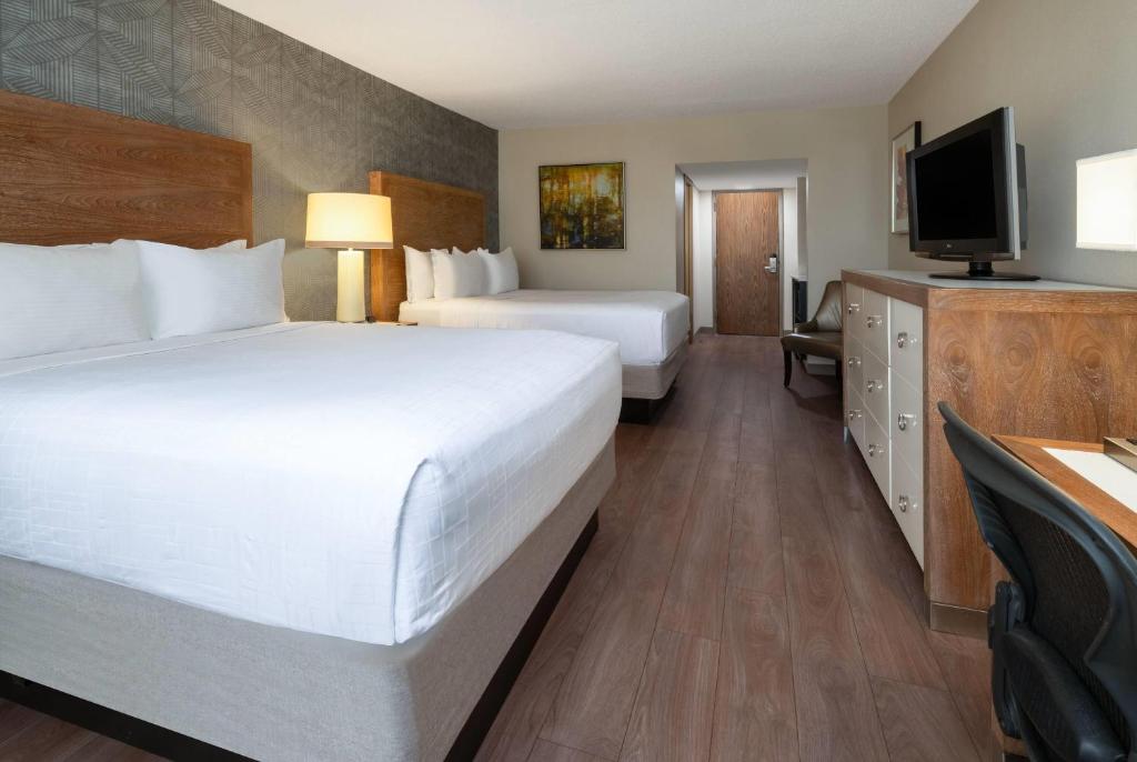 a hotel room with two beds and a flat screen tv at Wyndham Indianapolis Airport in Indianapolis