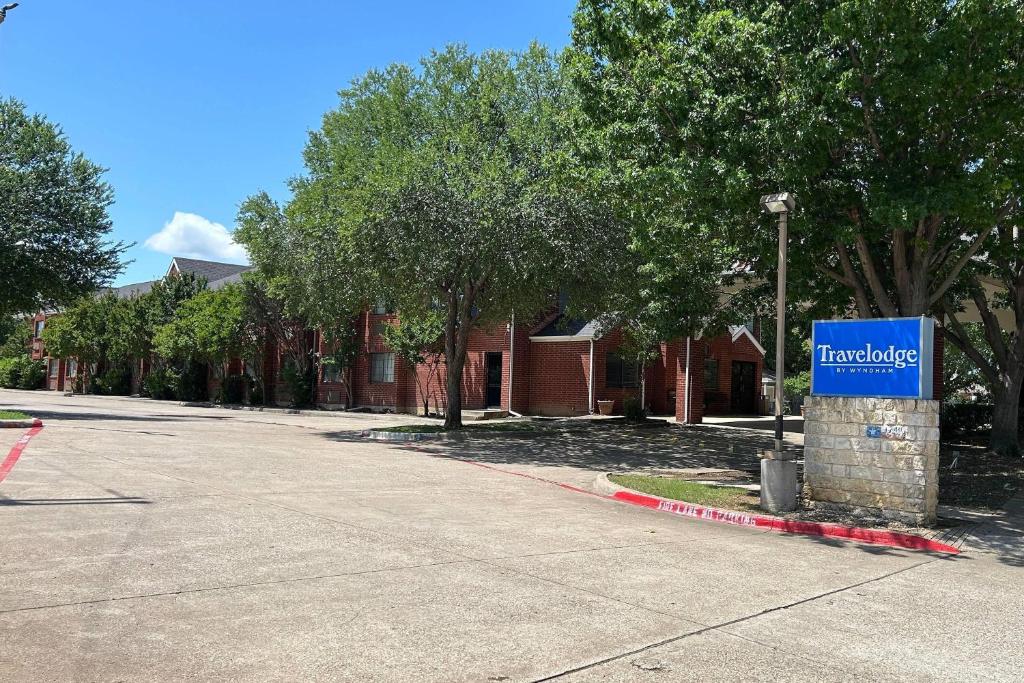 a street with a blue sign on a house at Travelodge by Wyndham Arlington/Dallas Area in Arlington