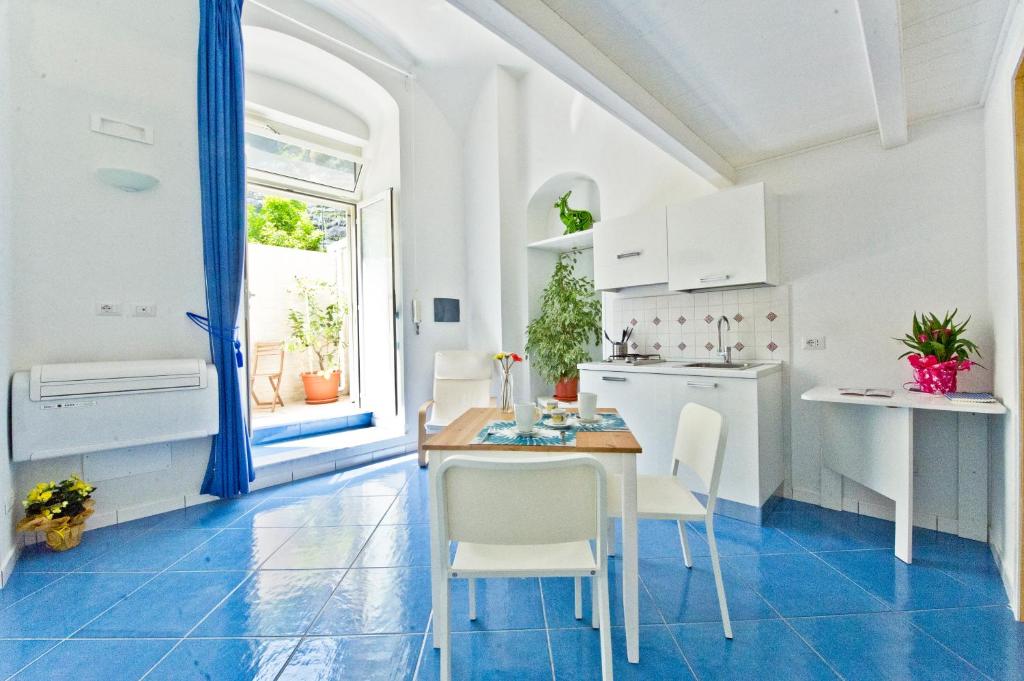 - une cuisine avec des placards blancs, une table et des chaises dans l'établissement Alfieri Rooms - Amalfi coast, à Atrani