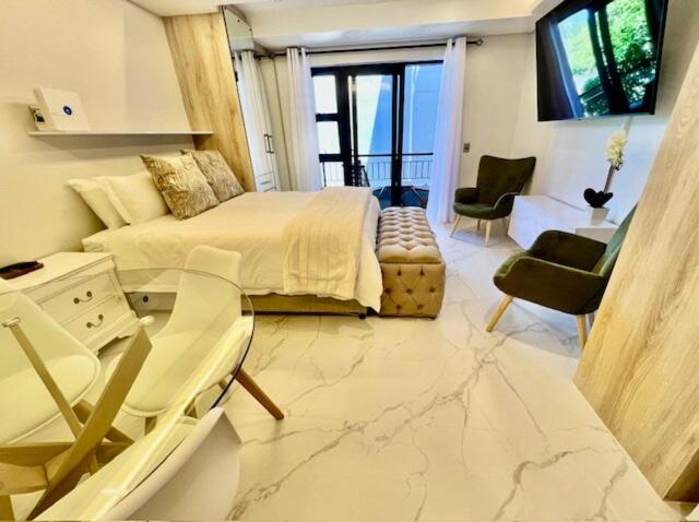 a bedroom with a bed and a table and chairs at 34 On The Den in Stellenbosch