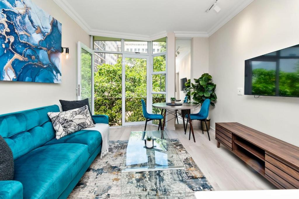 a living room with a blue couch and a table at CityPad 1 Bed w Balcony 5 mins to V&A, CTICC in Cape Town