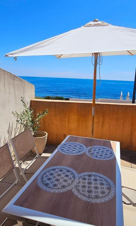 - une table avec un parasol et une chaise dans l'établissement Maisonette Vue Mer 180 - Terrasse & Jardin, à Roquebrune-sur Argens