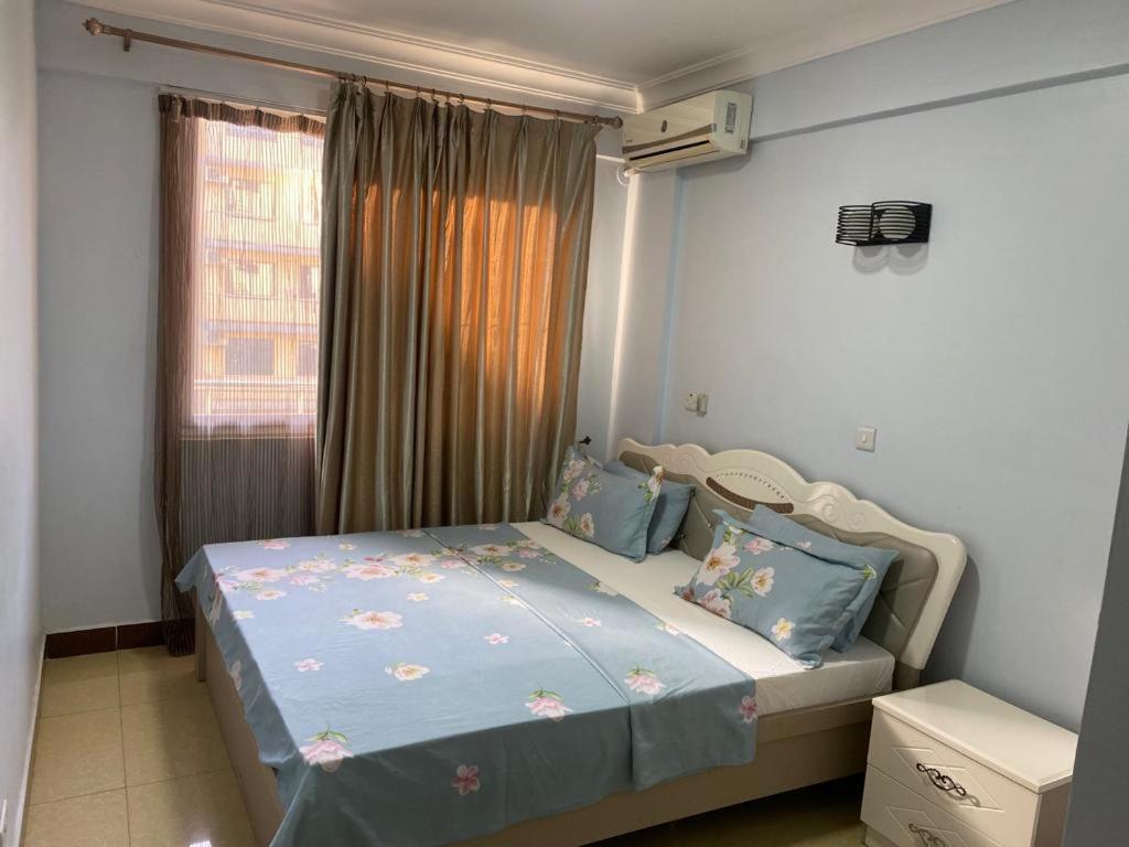 a bedroom with a bed with blue sheets and a window at Ocean view Home stay in Dar es Salaam
