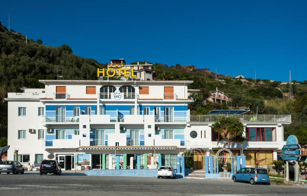 un hôtel sur une colline avec des voitures garées devant lui dans l'établissement Hotel La Carruba, à Cetraro