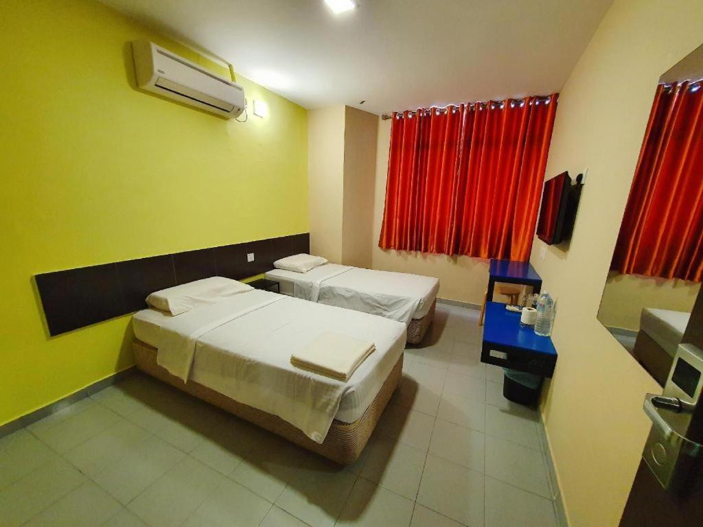 a hotel room with two beds and red curtains at Hotel Jelai Kuala Lipis (Jln Bk Bius) in Kuala Lipis