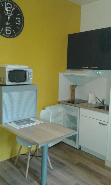une petite cuisine avec une table et un micro-ondes dans l'établissement SCI les THERMES 17, à Rochefort