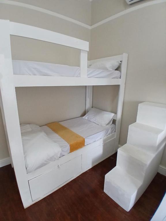 two white bunk beds in a room with wood floors at Biscuit Mill Woodstock Backpackers in Cape Town