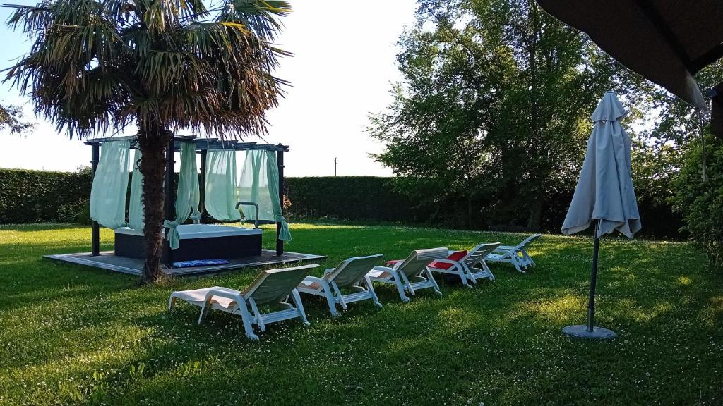 a group of chairs and an umbrella in the grass at Bed & Breakfast Orizzonte in Castello di Brussa