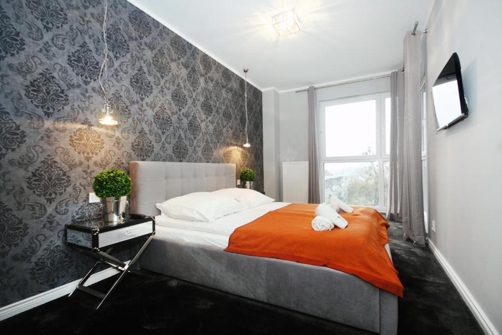 um quarto com uma cama com um cobertor laranja e uma janela em Livin Premium Apartments em Szczecin