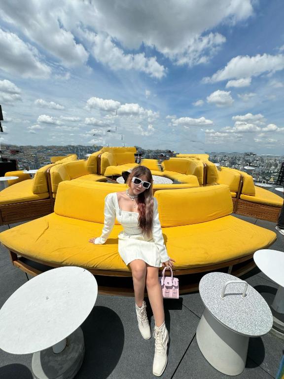 a young woman sitting on a yellow couch at Happy House TB in Thăng Bình