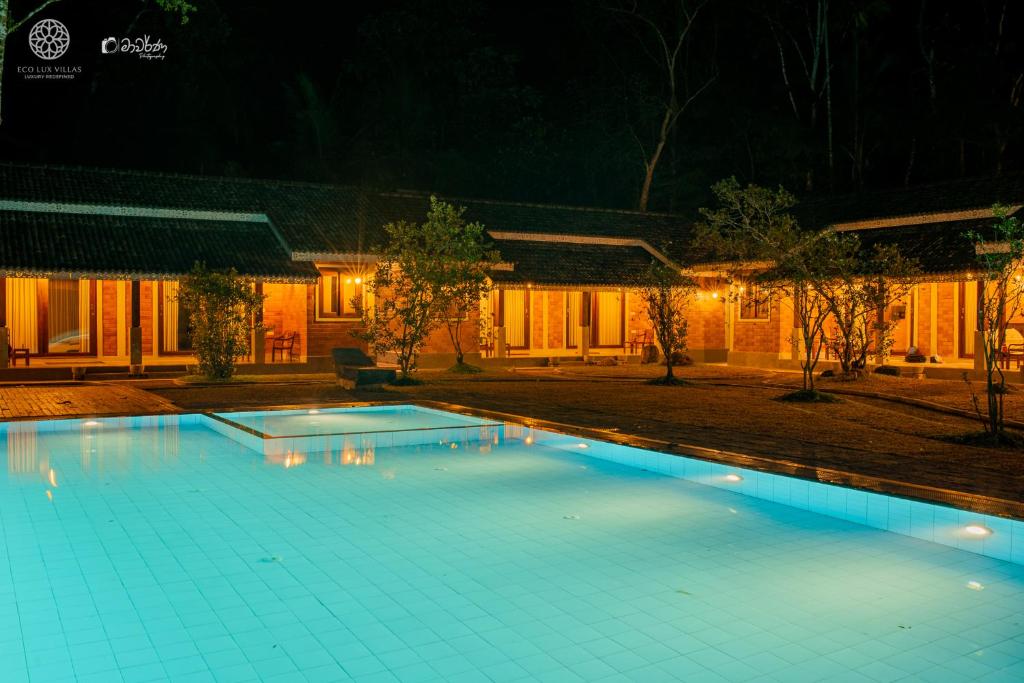 a swimming pool in front of a house at night at Eco Lux Villas in Ahangama
