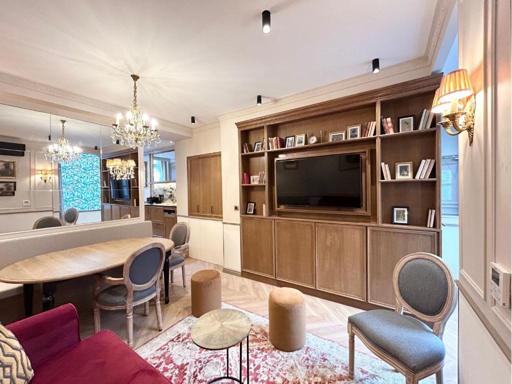 un salon avec une télévision, une table et des chaises dans l'établissement Merveil - Signature Suite - Tour Eiffel - Bourgogne, à Paris