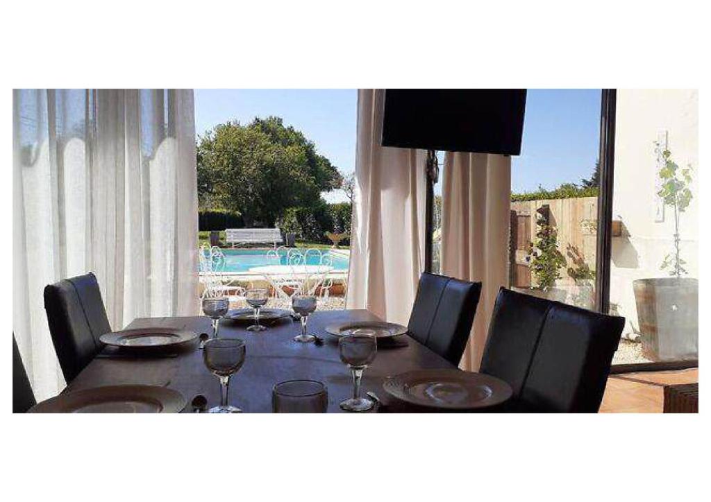 une table de salle à manger avec des chaises et une grande fenêtre dans l'établissement Gite Piscine Périgord, à Saint-Cyprien