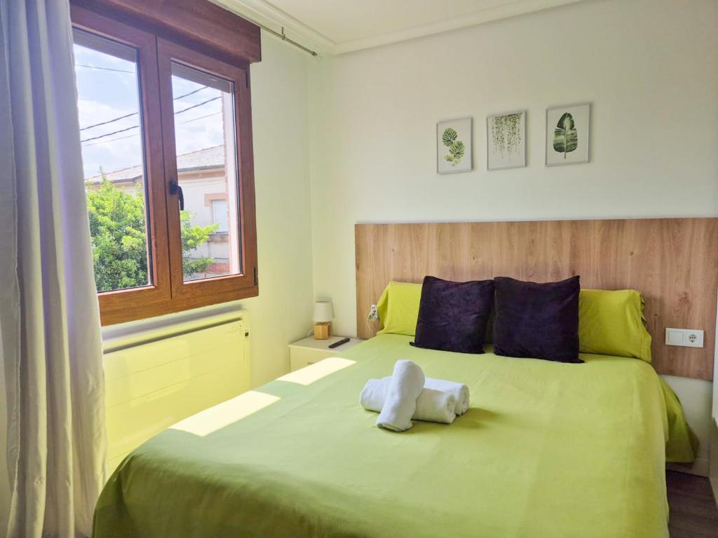 a white stuffed animal sitting on a green bed at La maruca loft 3000 in Santander