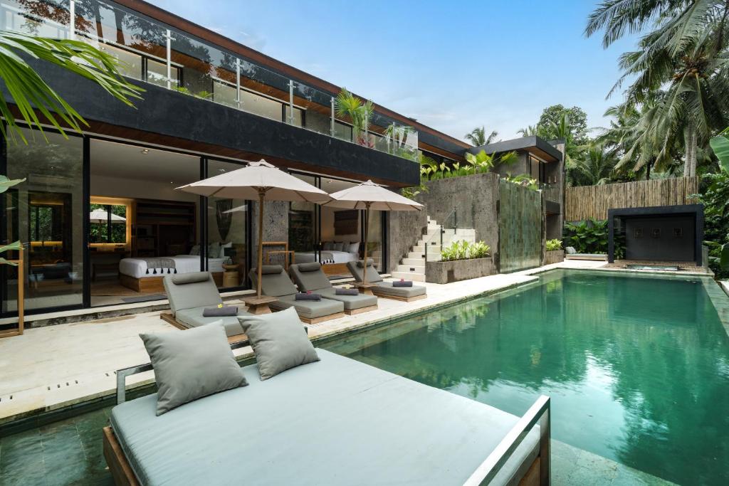 a house with a swimming pool with chairs and a tv at Villa Red Wine by BaliSuperHost in Ubud