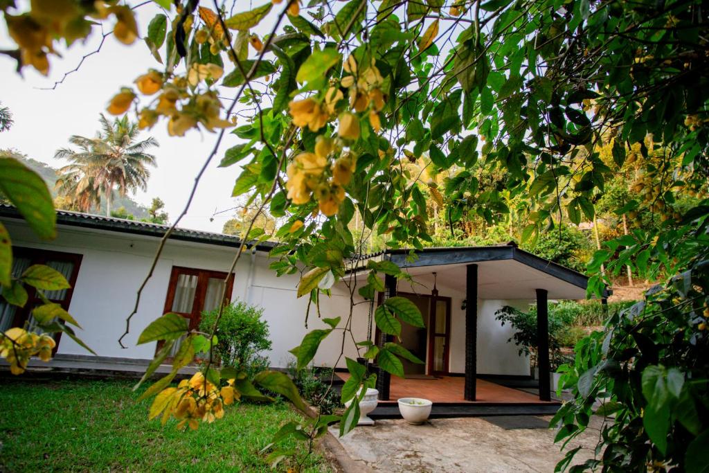 une petite maison blanche avec un toit noir dans l'établissement Royal Heritage Resort, à Kandy