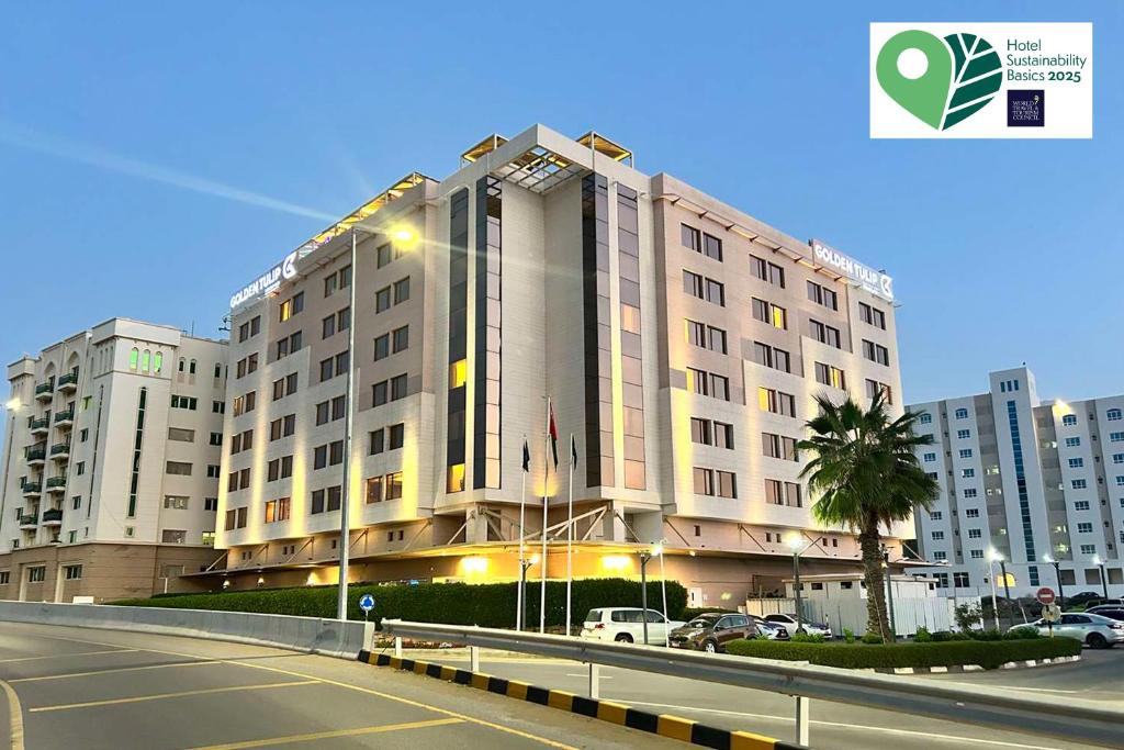 a large building with a palm tree in front of it at Golden Tulip Muscat in Muscat