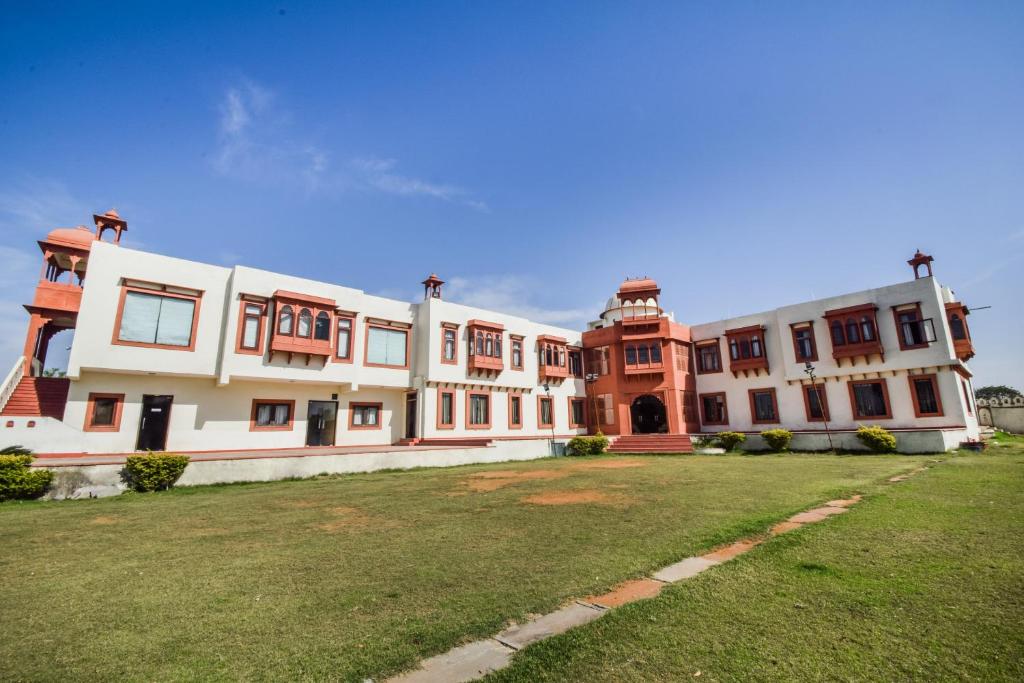 a large building with a grass yard in front of it at Hotel O Hadoti Resort in Bhilwara