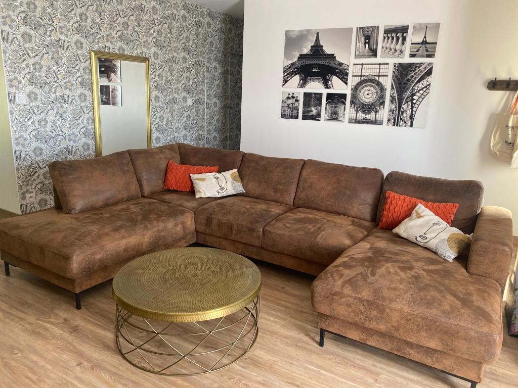 un salon avec un canapé marron et une table dans l'établissement Maison parc clos 15mn du circuit proche centre, à La Celle-sous-Gouzon