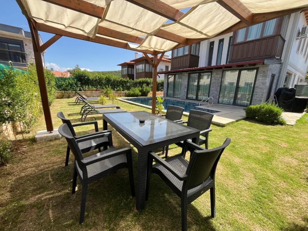 un tavolo e sedie sotto un ombrellone in un cortile di Derya Beach Agullu Villa 3 a Kaş